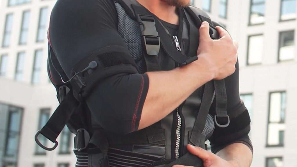 A man adjusts his black weighted vest before exercise.