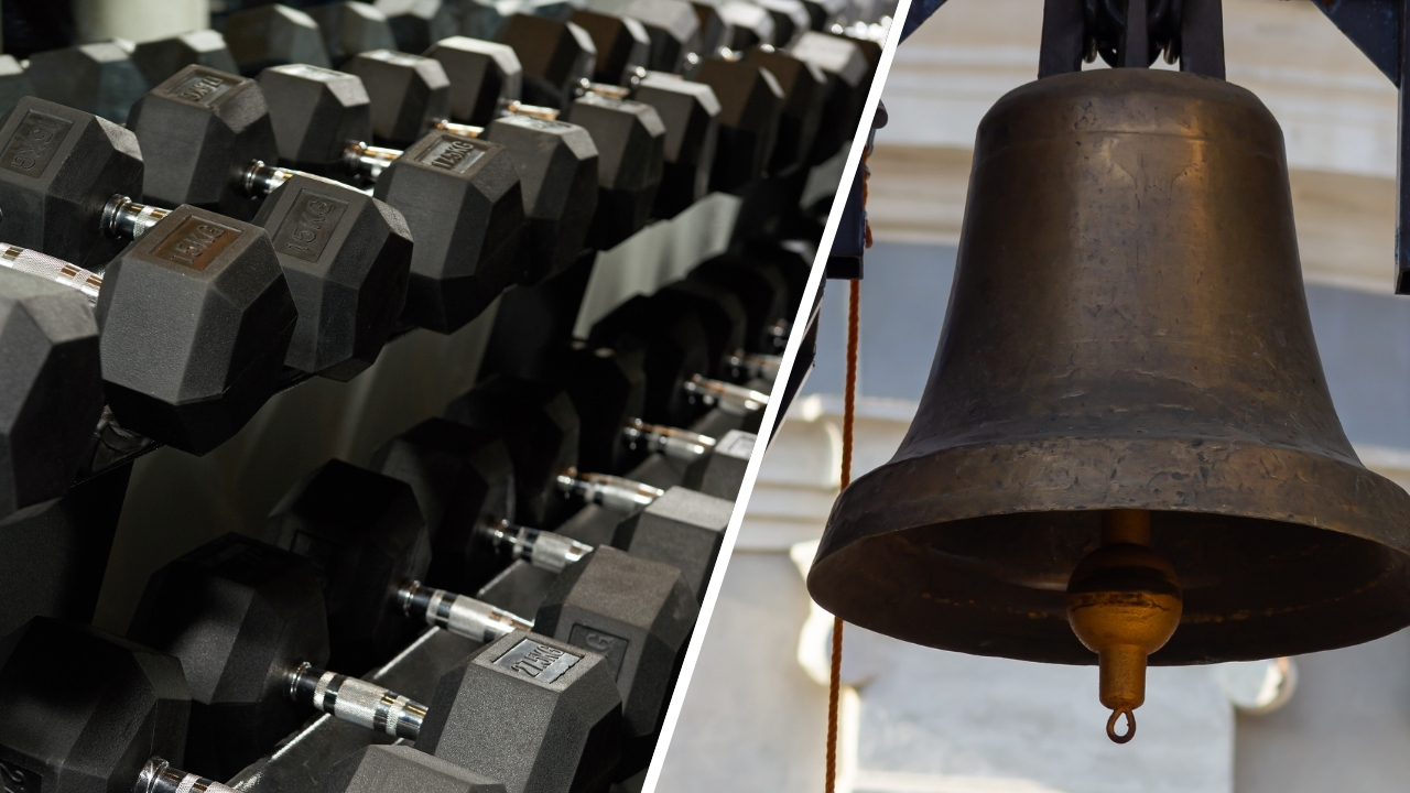 Dumbbells on a gym rack beside a large hanging bell.