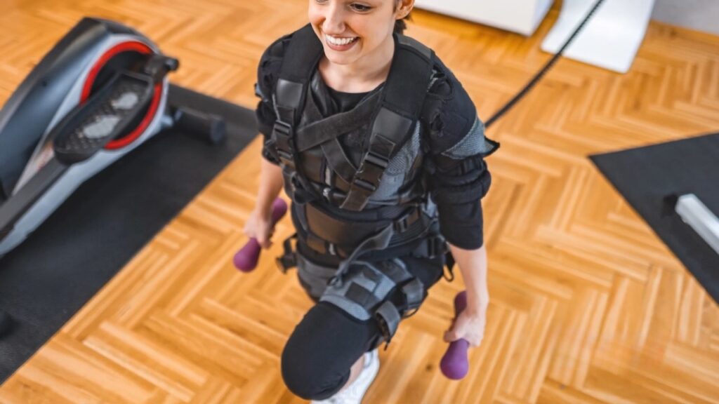 A woman performs a lunge with dumbbells and a weighted vest.