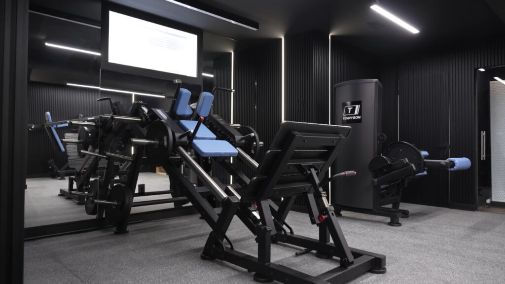 Basement gym with black walls, bright LED lights, wall mirrors, and weight machines.