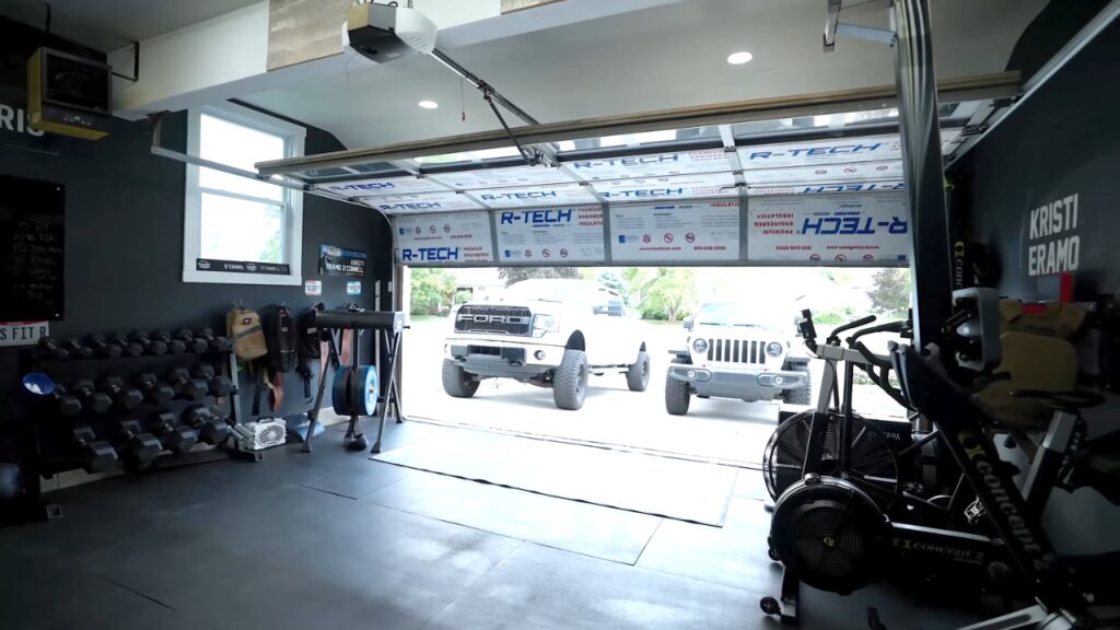 A full garage gym with dumbbells, cardio machines, and open floor space.