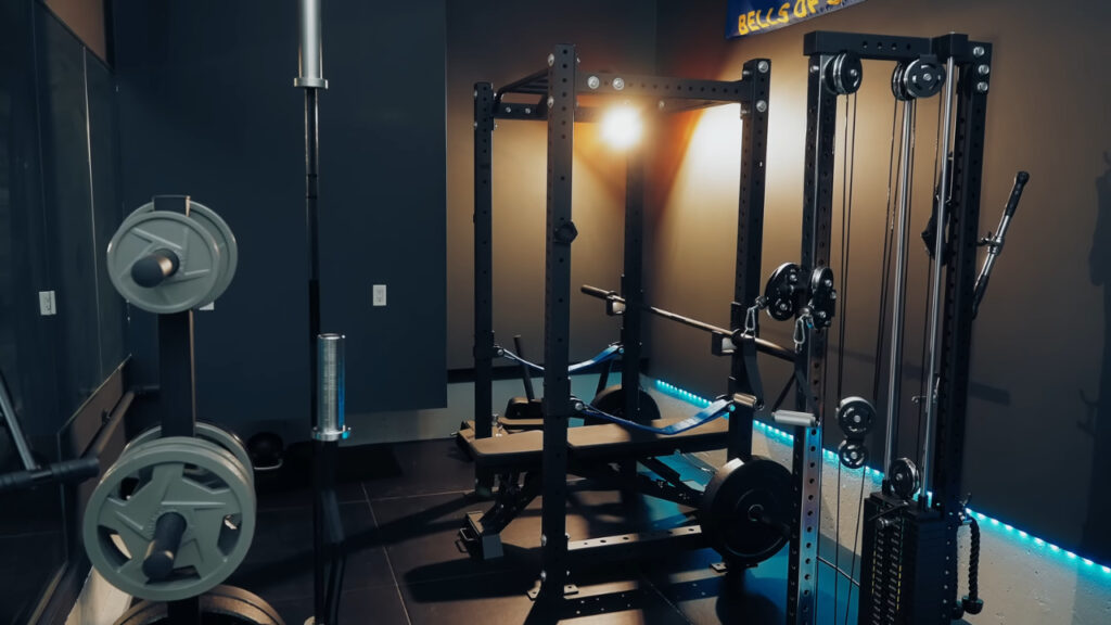 A compact home gym with a weight rack, bench, cable machine, and weight plates.