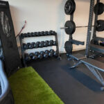 A home gym with dumbbell racks, weight benches, a squat rack, and exercise equipment.