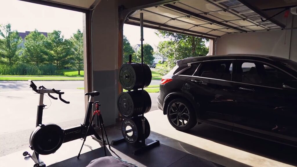 Exercise bike and weight plates share garage space with a parked SUV.